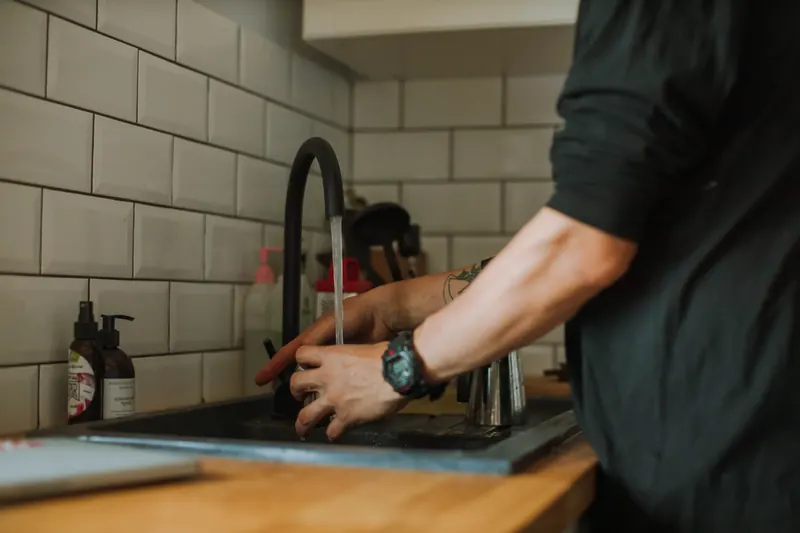 Plumber adjusting a kitchen faucet at the sink