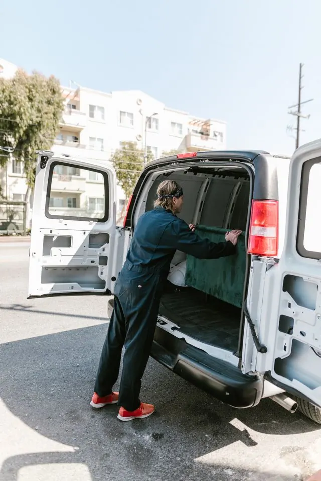 Plumber unloading equipment from the back of a white service van