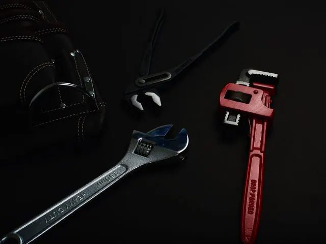 Pipe wrench, adjustable wrench and pliers on a dark surface