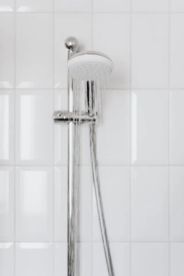 Wall-mounted shower head on white tile
