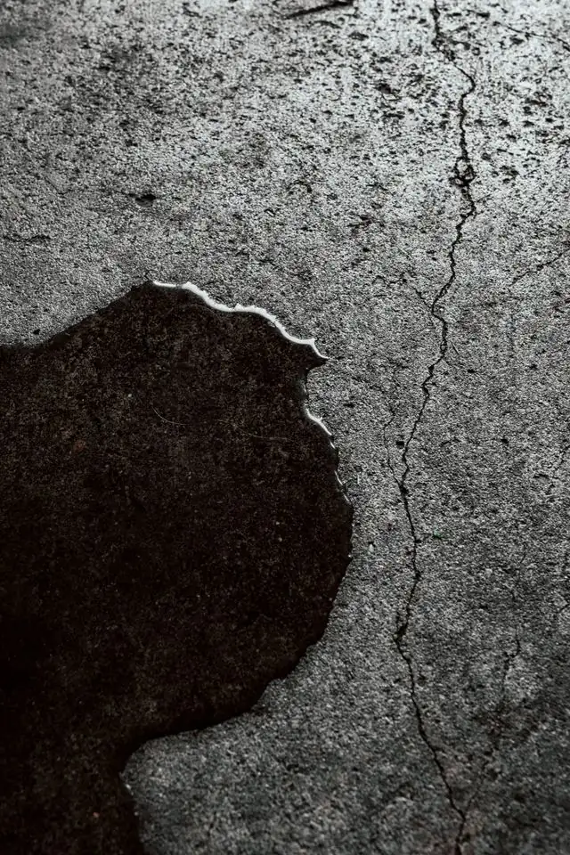 Dark wet patch spreading across a bare concrete slab