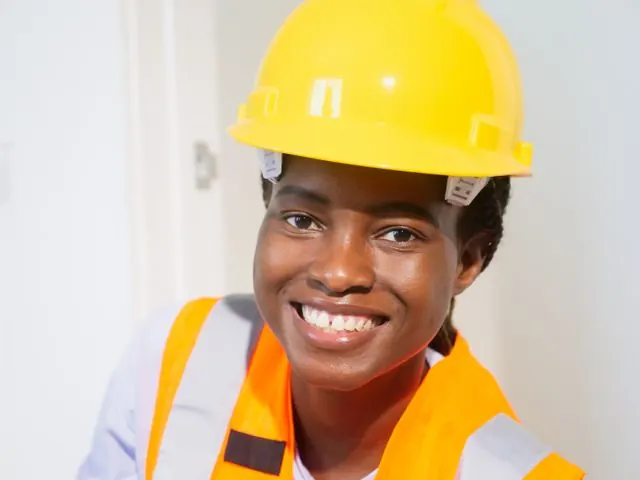 Smiling plumber in a yellow hard hat and orange safety vest