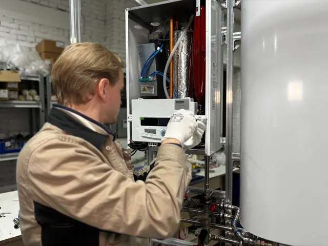 Technician in gloves servicing the controls of a water heater
