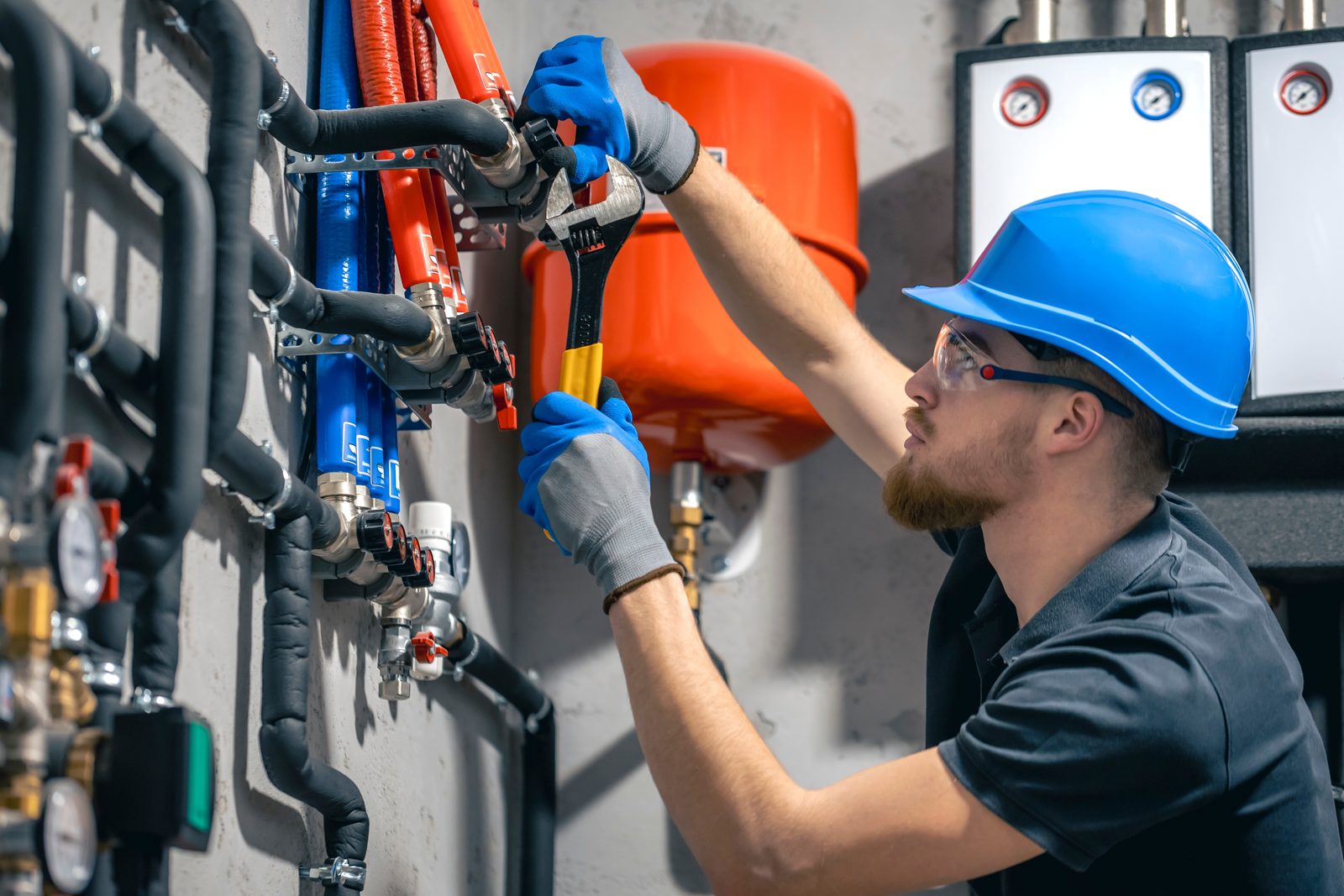 Licensed plumber tightening a fitting on a red and blue PEX repipe manifold