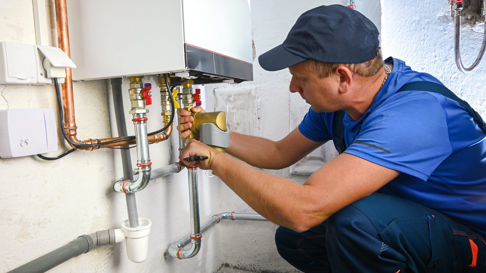 Plumber connecting gas and water lines to a wall-mounted tankless water heater