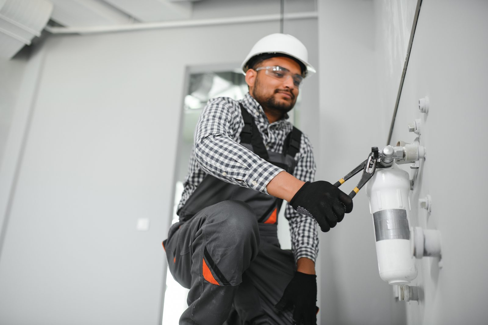 Plumber installing a whole-house water filter cartridge on a wall-mounted system